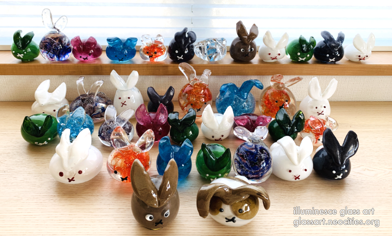 A variety of bright glass rabbits, all in different colors and sizes.