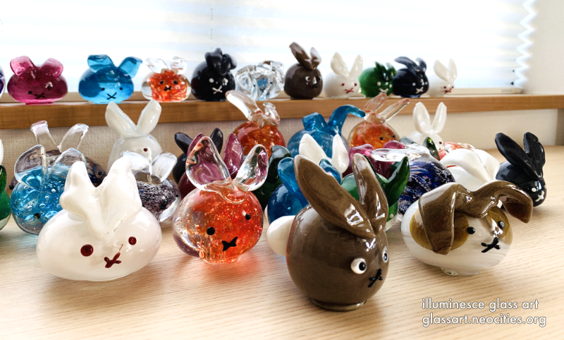 A variety of bright glass rabbits, all in different colors and sizes.