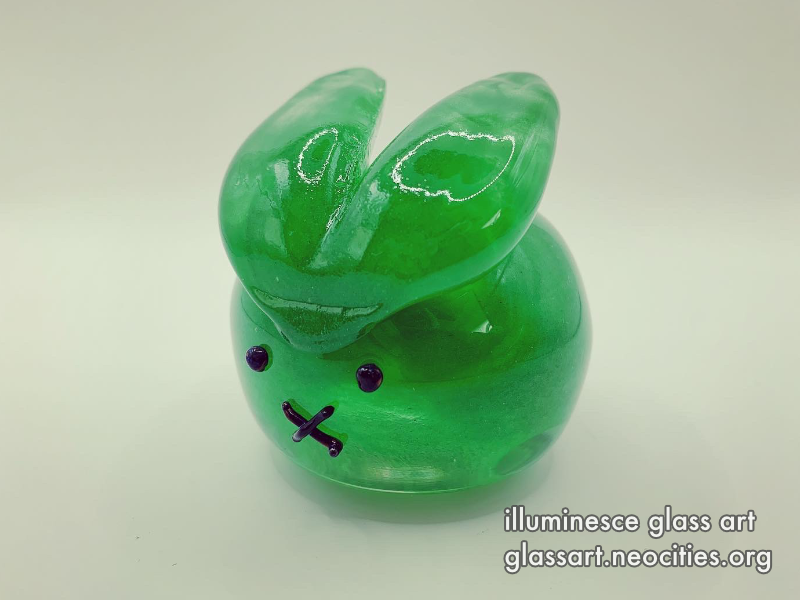 A back view of a jade green, round rabbit.