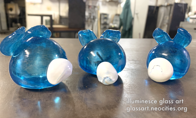 A back view of three bright blue, round rabbits.