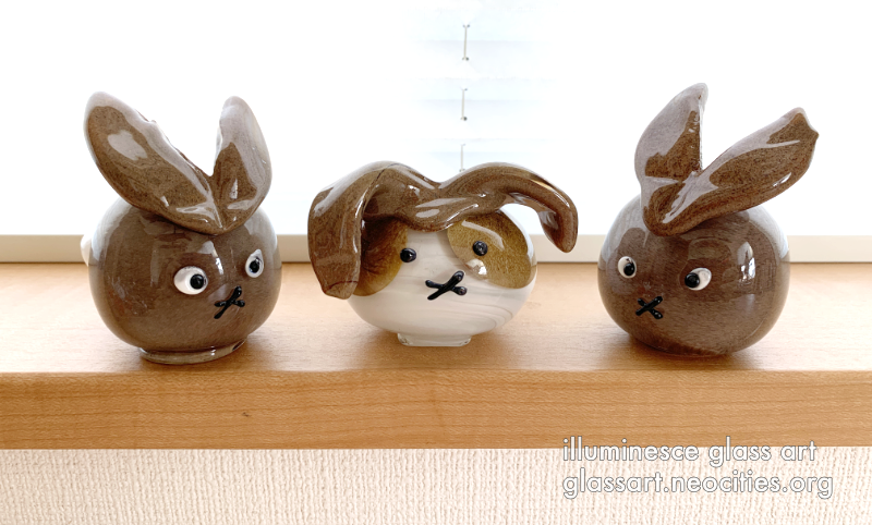 Three rabbits, two brown and one spotted. They are orbular.